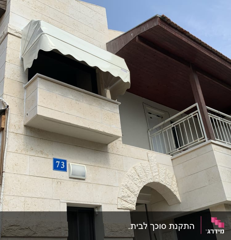 סוכך לבן מעל מרפסת בקומה שנייה של בניין.